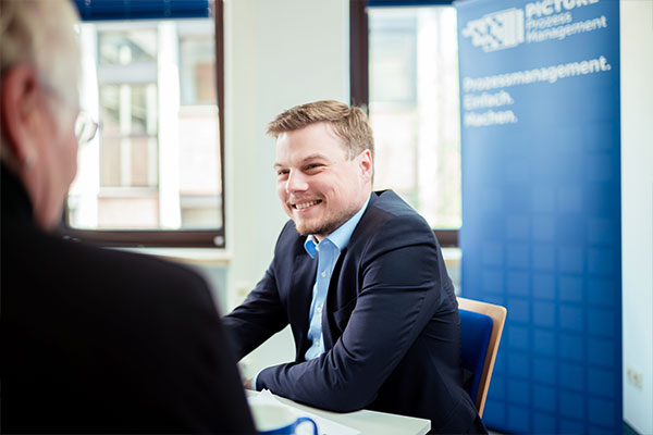 Mann im Gespräch mit einer weiteren Person am Tisch