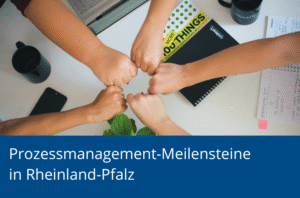 Mehrere Hände stoßen in der Mitte eines Schreibtischs zusammen, umgeben von Laptop, Notizen und Pflanze, als Symbol für Teamarbeit.
